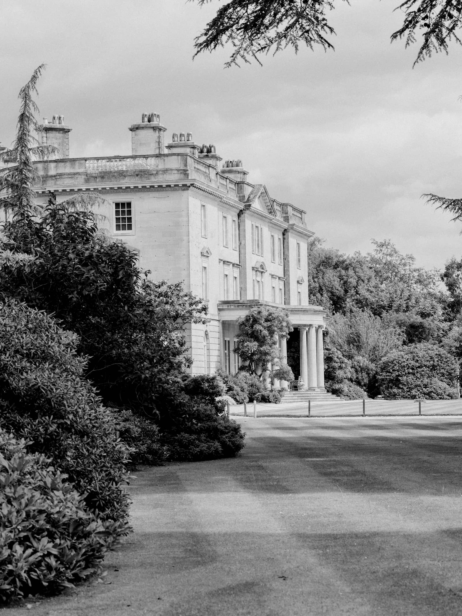 A large country house seen across a striped lawn, with mature trees